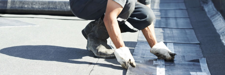 Worker installing roofing material on a flat commercial roof