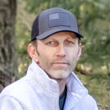 Man in gray jacket and cap in a natural outdoor setting